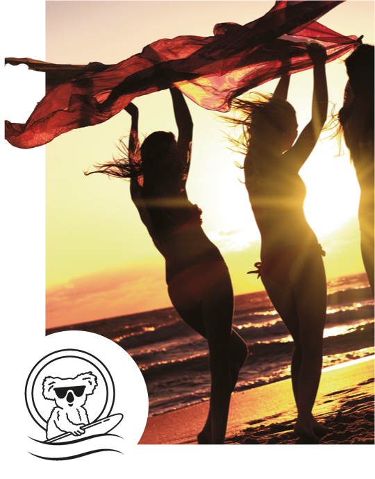 Friends on a beach at sunset holding a scarf overhead